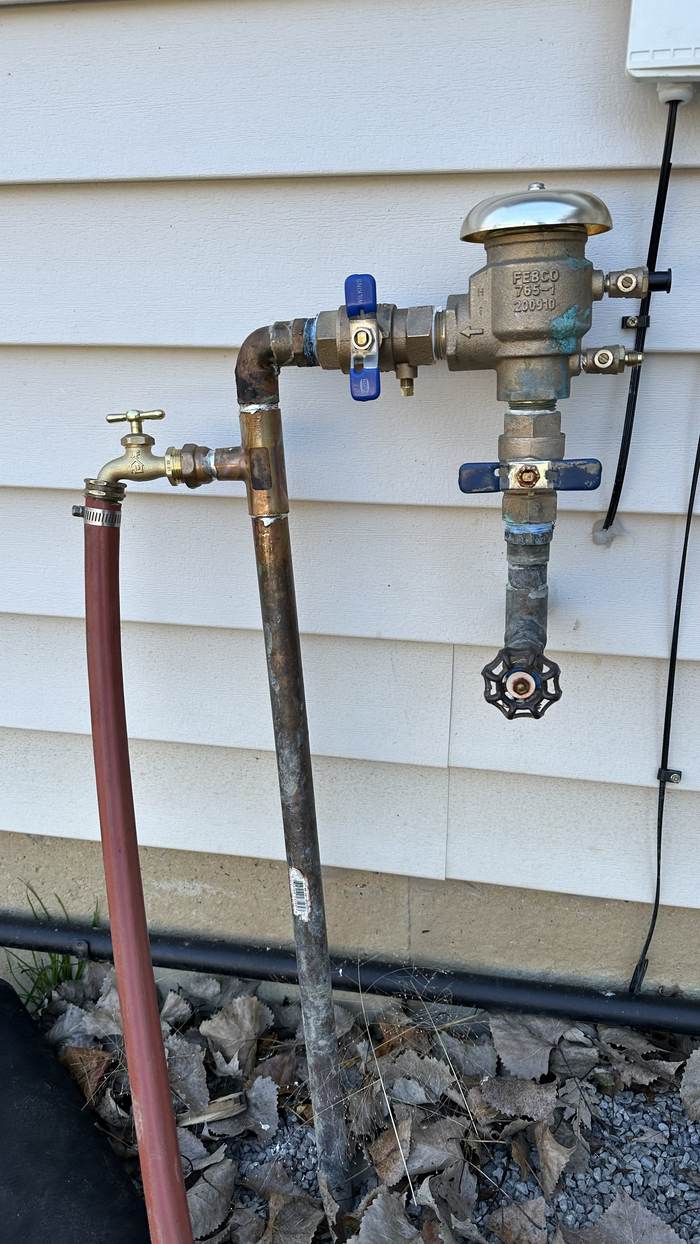 Backflow preventer assembly mounted on the side of a house